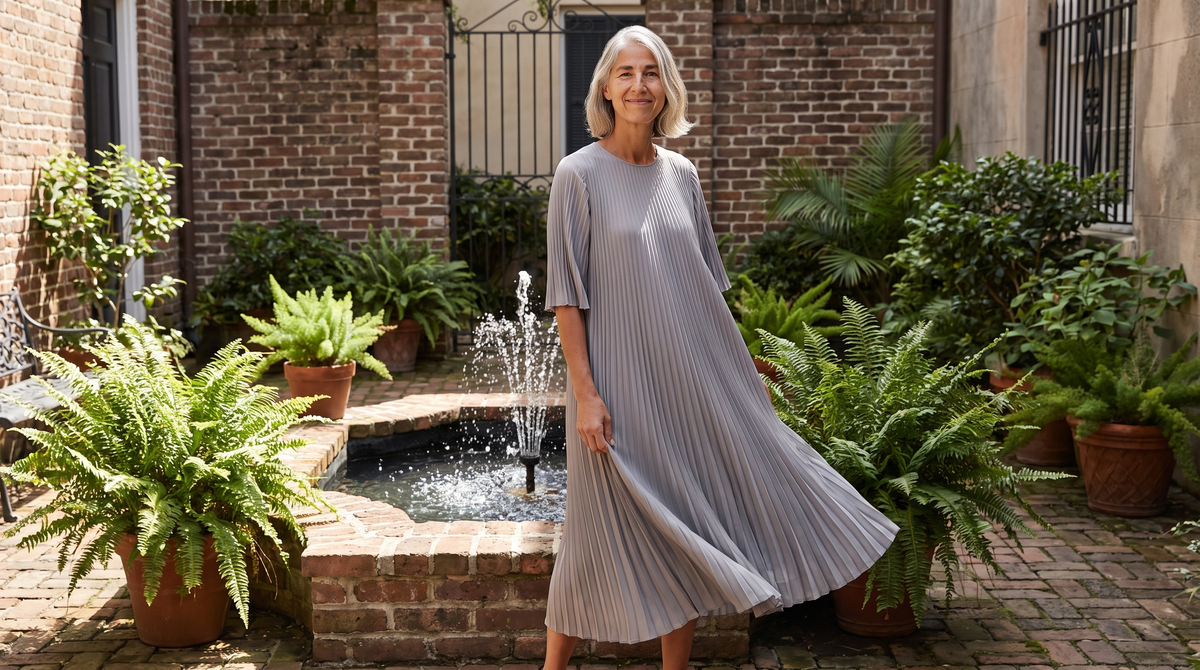 A woman wearing a dove grey finely pleated midi dress that catches the light as it moves — Pleated Dresses